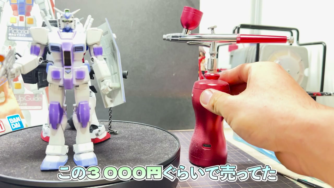 100均の水性塗料で仕上げた白×紫のHGガンプラ完成品と、使用したエアブラシスターターキット。「この3000円ぐらいで売ってた」の字幕。