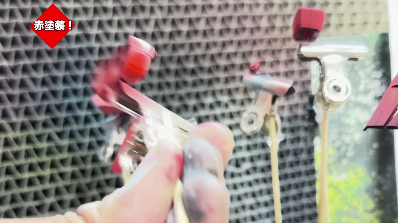 赤く塗装されたガンプラパーツをエアブラシで吹いている様子。「赤塗装！」の字幕。