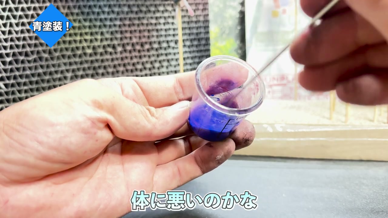 透明なカップにブルーのアクリルガッシュを入れて水で希釈している様子。「青塗装！」「体に悪いのかな」の字幕。
